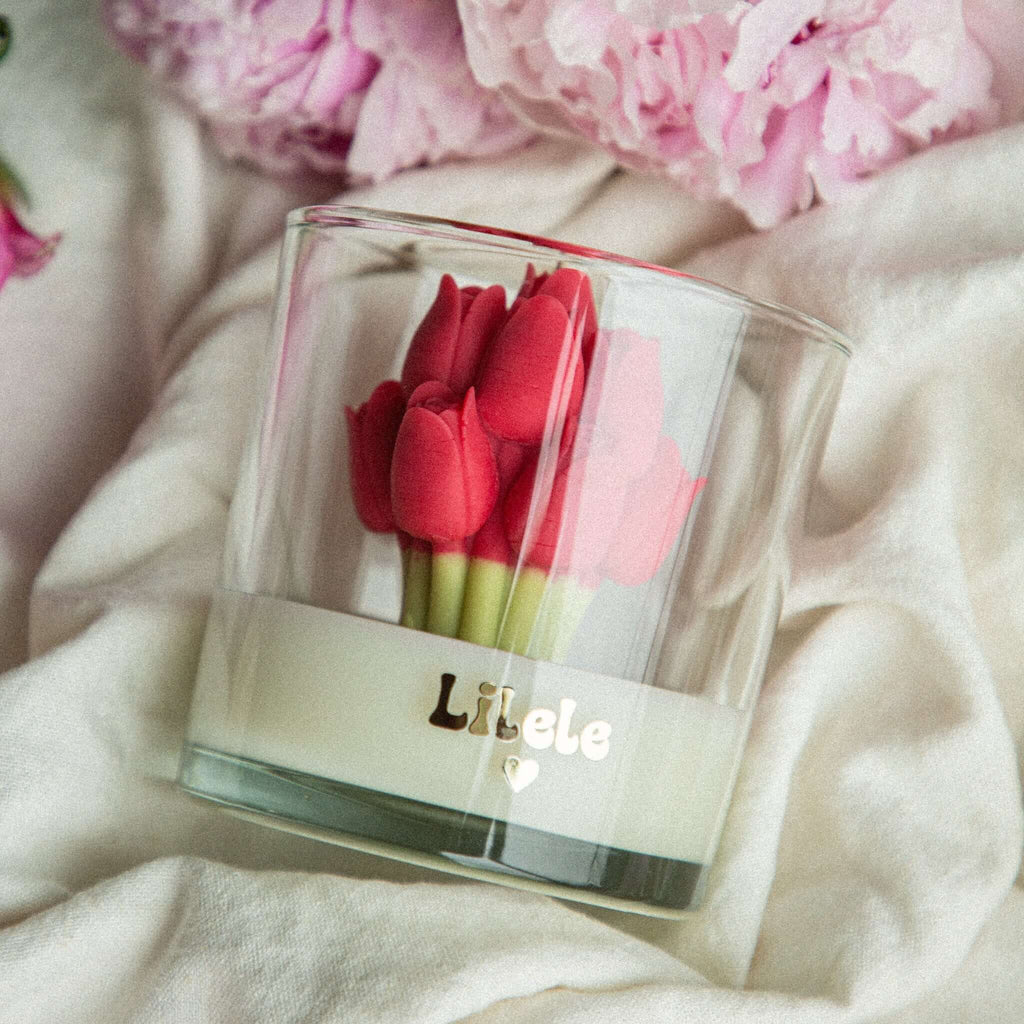 Eco-friendly soy candle with red tulip embeds, styled on fabric with pink peonies