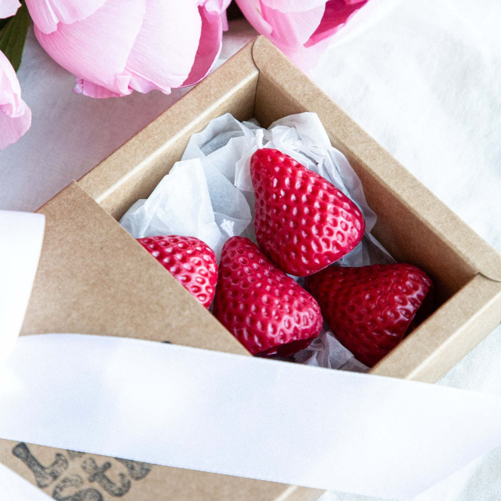 Handmade strawberry-shaped beeswax candles in a kraft gift box 