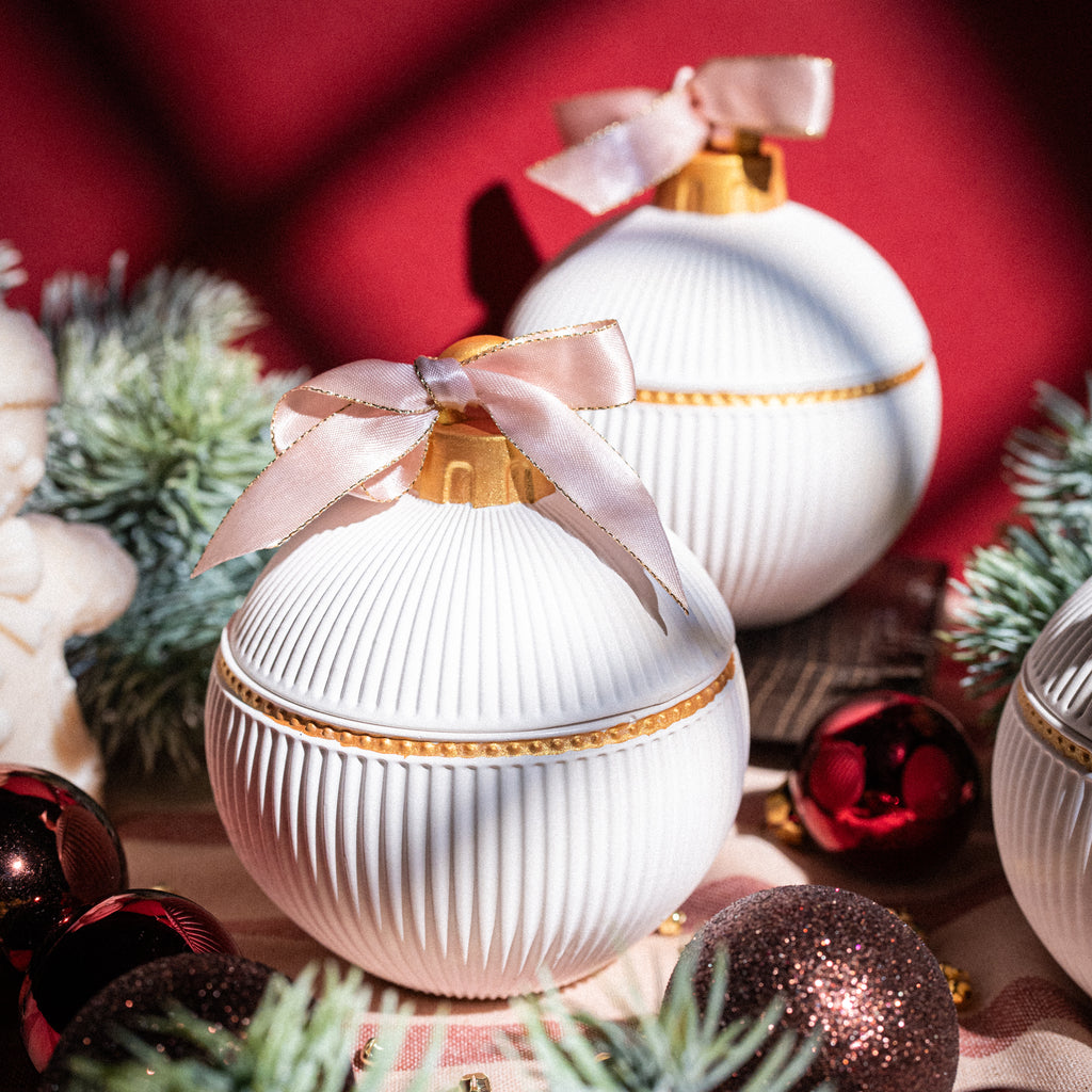 Ziemassvētku svece bumbas formā ar zelta rotājumu un rozā lentīti